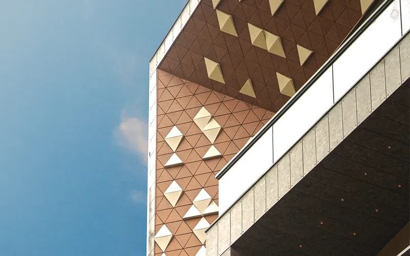 Triangular faceted panel facade in terracotta and champagne gold on a commercial building